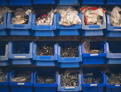 Rows of shelves with blue trays stacked side by side with nuts and bolts in them